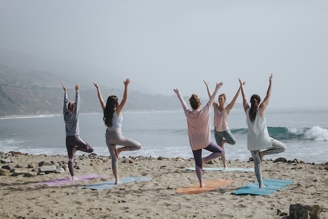 Five Women Practicing yoga on the beach