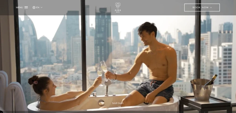 A woman and man relax in a sleek, modern bathtub with champagne, overlooking the city skyline through large windows—a scene reminiscent of the best hotel website design.