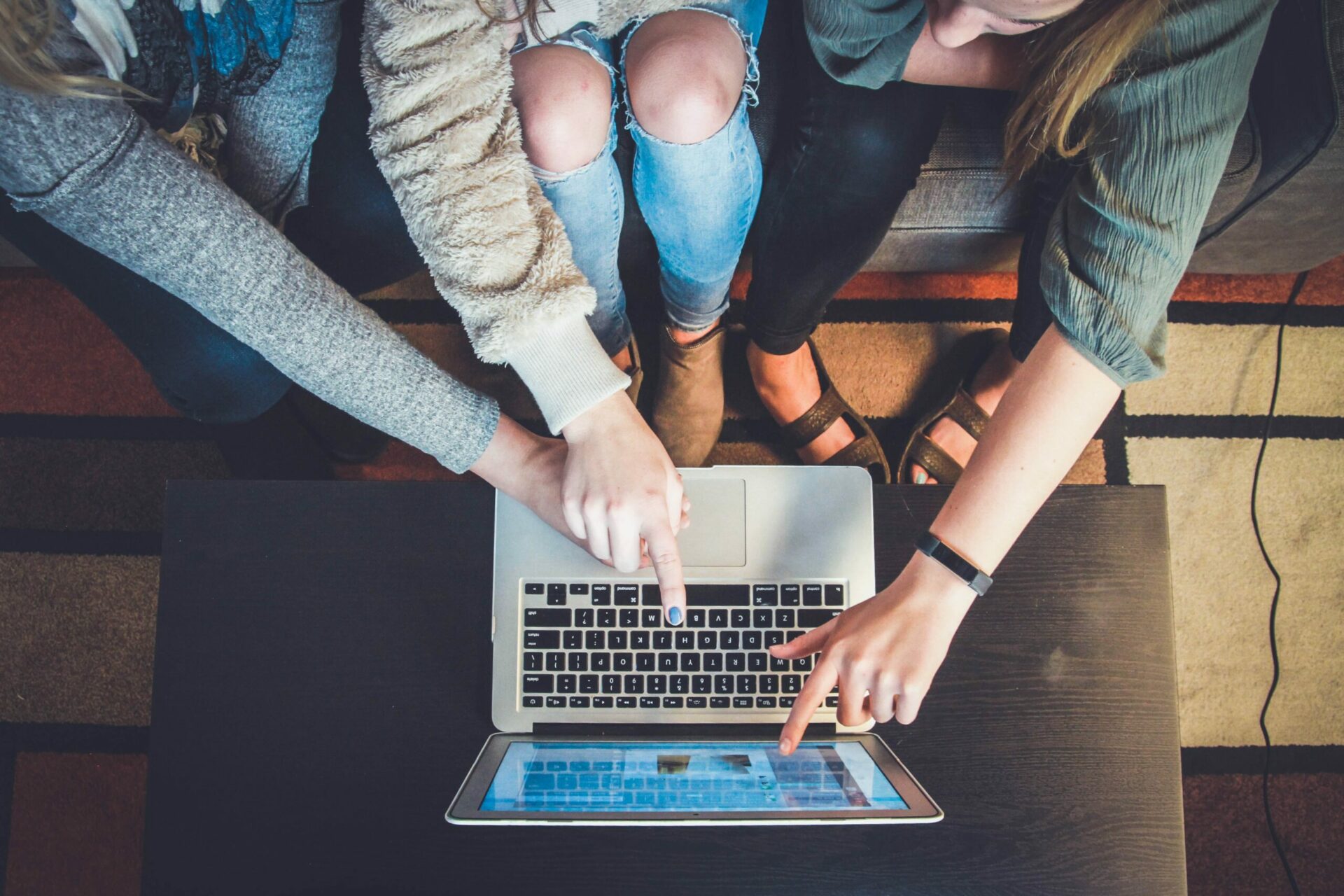 three women pointing at a laptop